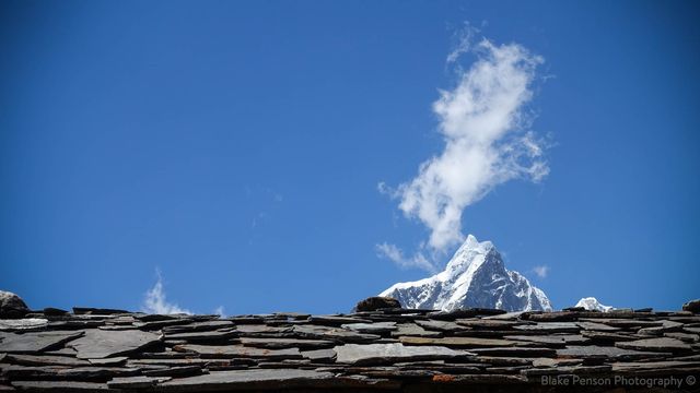 Mountain peeking over a slate roof top.